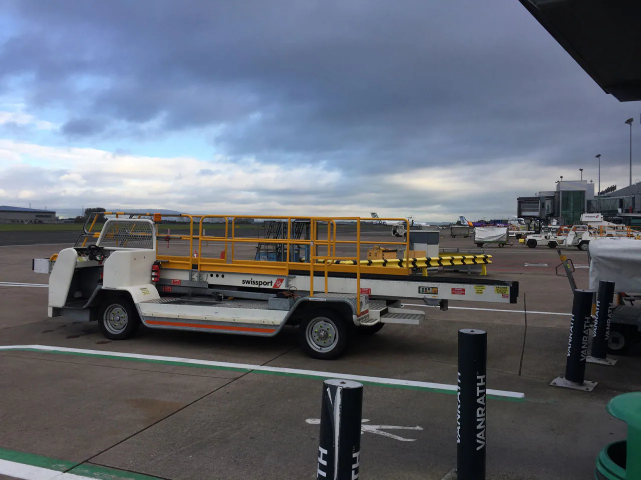 Airport ground-service equipment parked on an apron beneath a cloudy sky.