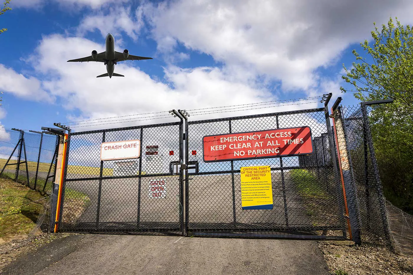 Aircraft flying over a restricted airport crash gate and security perimeter.